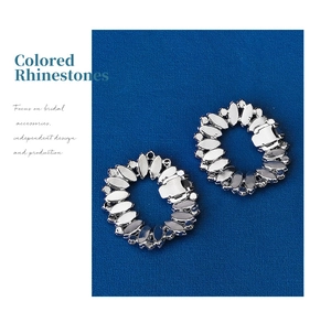 Macro view of oval hollow rhinestone shoe clips with colorful crystals on blue fabric