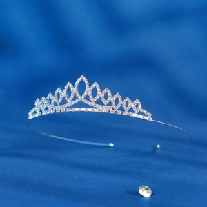 Close-up of sparkling diamond tiara for flower girls on blue silk background