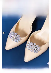 Gros plan d'un clip à chaussure en zircon sur escarpin beige avec un fond bleu profond