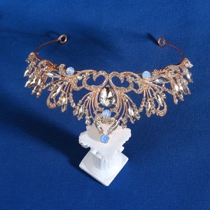 Close-up of luxury rose gold bridal crown with blue rhinestones on a white pedestal
