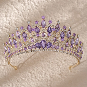 Detailed view of luxury gold crown with purple and clear rhinestones on textured background