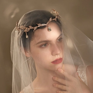 Détail d'une couronne de mariée en or rose avec feuilles ciselées et pendentifs brillants