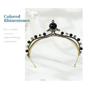 Detail of vintage gold bridal tiara with black rhinestones and pearls on white texture