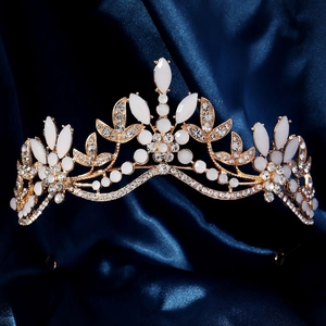 Elegant gold bridal crown with white rhinestones on dark blue silk background