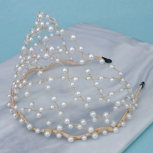 Detail of elegant gold mesh crown headband with white pearls and marble fabric background