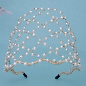 Detail of hand-woven gold wire mesh headband with white pearls for wedding parties
