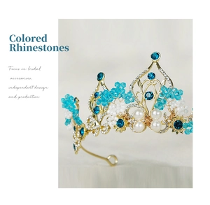 Close-up of blue crystals and white pearls set in a golden baroque bridal crown