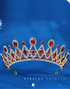 Detail view of luxury gold bridal crown with red rhinestones on blue silk background