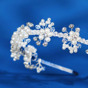 Exquisite bridal headband with white pearls and sparkling crystal flowers on a blue background