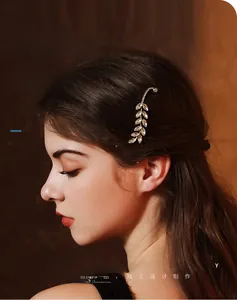 Close-up of a leaf-shaped rhinestone hair clip worn on model side hair with vintage style