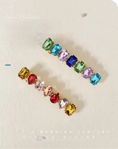 Detailed close-up of colorful rhinestone hair clips with gold metal base and bright crystals