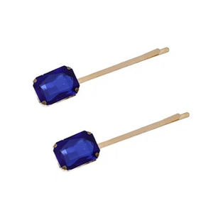 Close-up of golden bobby pins featuring rectangular deep blue faceted gemstones