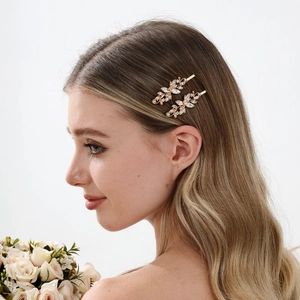 Macro detail of two vintage gold flower hair clips with rhinestones worn by a model