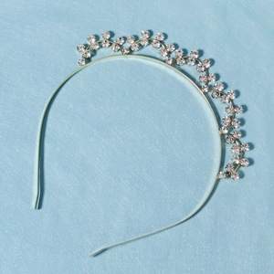 Elegant gold metal headband with sparkling floral rhinestone clusters on a light blue background