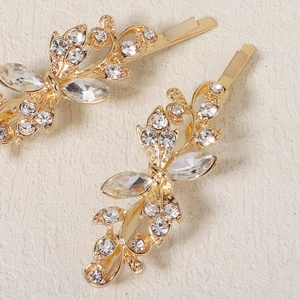 Detailed close-up of golden hair pins with elegant floral patterns and clear rhinestones