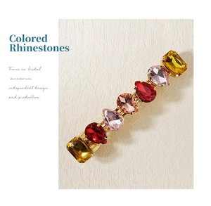 Detail of colorful rhinestones in square and teardrop shapes on a gold hair clip