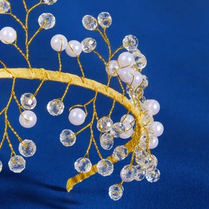 Elegant handmade gold bridal headband with white pearls and crystals on blue background