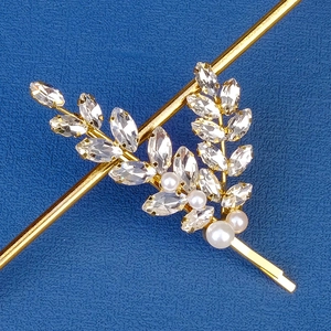 Macro shot of gold leaf hair clip with marquise crystals and elegant white pearls