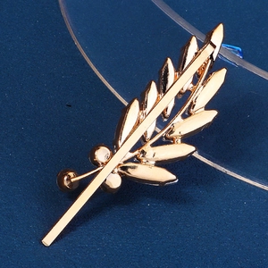 Detailed back view of golden leaf brooch with sparkling crystals on dark blue background