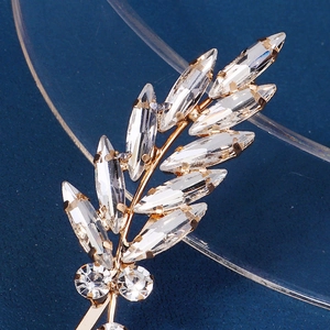 Detail of golden leaf hair clip with marquise-cut zircons and polished metal base