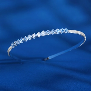 Détail d'un serre-tête argenté avec zircons carrés sur un tissu en soie bleue