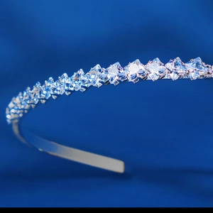 Vue macro d'un serre-tête fin en argent avec cristaux de zircon carrés sur soie bleue luxe