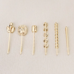 Detail of 6-piece golden hair clip set with rhinestones and pearls on white surface