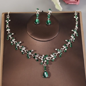 Detail view of bridal jewelry set with green teardrop gemstones and silver floral necklace