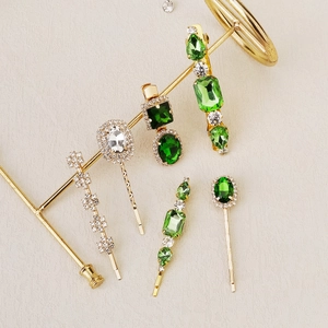 Detail of vintage gold-plated hair clips set with green and clear faux crystals