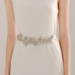 Dettaglio macro dell'elegante cintura da sposa con strass su nastro di raso avorio