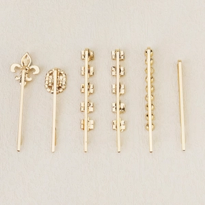 Detail view of six gold-tone metal hair clips with vintage floral and geometric patterns