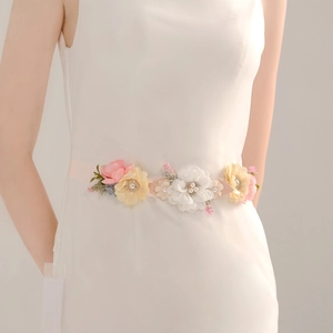 Close-up of handmade fabric flowers on a bridal belt with pearls and rhinestones