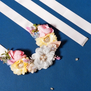 Detail of bridal floral belt with silk flowers, faux pearls and rhinestones on white ribbon