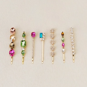 Close-up of seven assorted gold alloy hair clips with colorful rhinestones and pearls