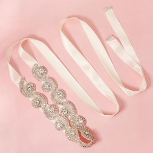 Détail de ceinture de mariée en satin ivoire avec motif de vagues en strass brillant
