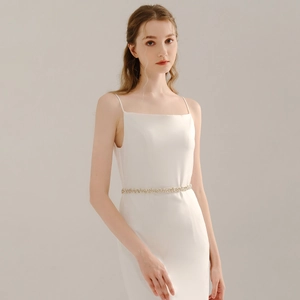 Detailed view of handmade pearl and rhinestone bridal belt on a white wedding dress
