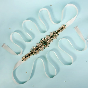 Close-up of emerald green and clear crystal bridal belt with white satin ribbon