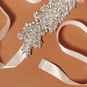 Close-up of handmade bridal sash with crystal rhinestones and white satin ribbon ties