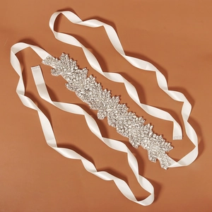 Close-up of a bridal wedding belt featuring sparkling rhinestone floral motifs on white satin ribbon