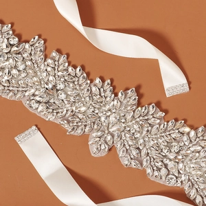 Detail of bridal rhinestone belt with intricate crystal floral patterns and white ribbon