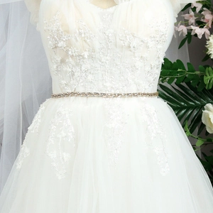 Elegant gold bridal waist belt with sparkling rhinestones on a white lace wedding dress