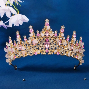 Golden bridal tiara with pink crystals and white rhinestones on dark background
