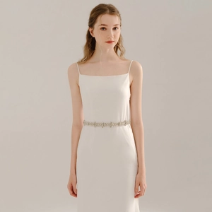 Gros plan d'une ceinture de mariée en strass cousue main sur une robe blanche