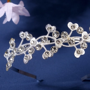 Detailed close-up of a silver crown headband with heart and flower crystal rhinestones