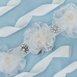 Close-up of white organza flowers and sparkling marquise crystals on a bridal belt sash