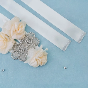 Vue détaillée de la ceinture de mariée en satin blanc avec roses et strass brillants