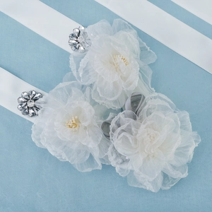 Detailed close-up of white mesh flower bridal belt with sparkling rhinestones and ribbon