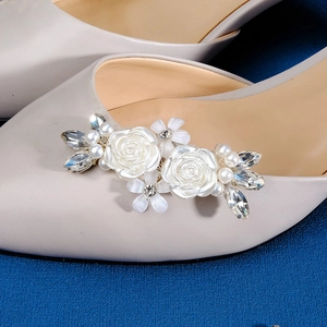 Dettaglio macro della clip per scarpe con camelia in resina bianca, perle e strass