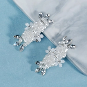 Paio di eleganti clip per scarpe a camelia bianca con perle e strass su marmo