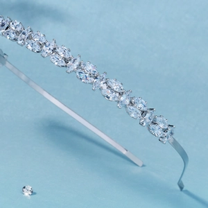 Détail d'un serre-tête argenté avec zircons taille marquise sur un fond bleu clair épuré